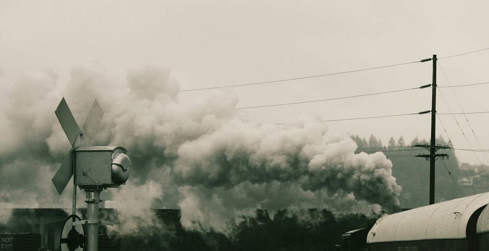 Steam train emitting smoke against sky