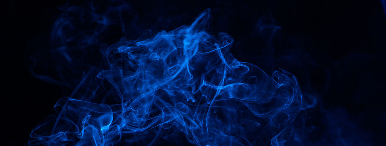 Conceptual image of blue color smoke isolated on dark black background, halloween concept design.