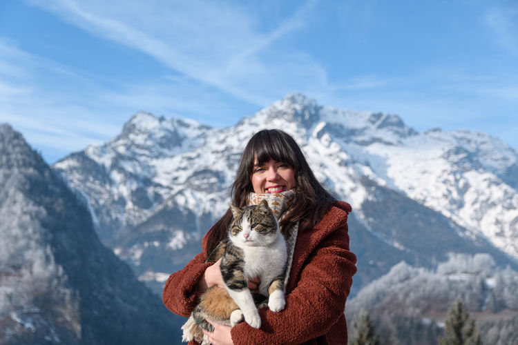 Portrait of a young woman holding a cat. mountains, winter, depth of field.