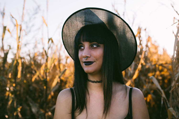 Portrait of woman wearing hat standing against plants