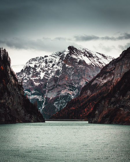 Scenic view of lake by snowcapped mountains against sky