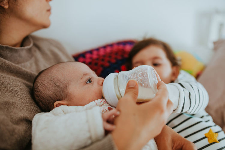 Close-up of mother feeding baby boy while sitting at home