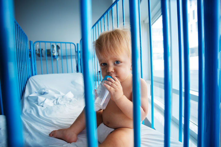 Portrait of cute boy looking through crib