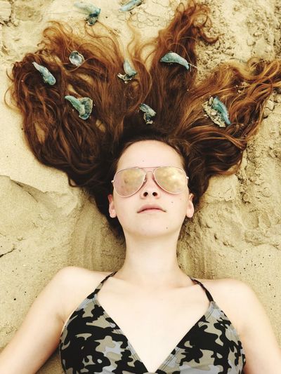 Portrait of teenage girl lying on sand at beach