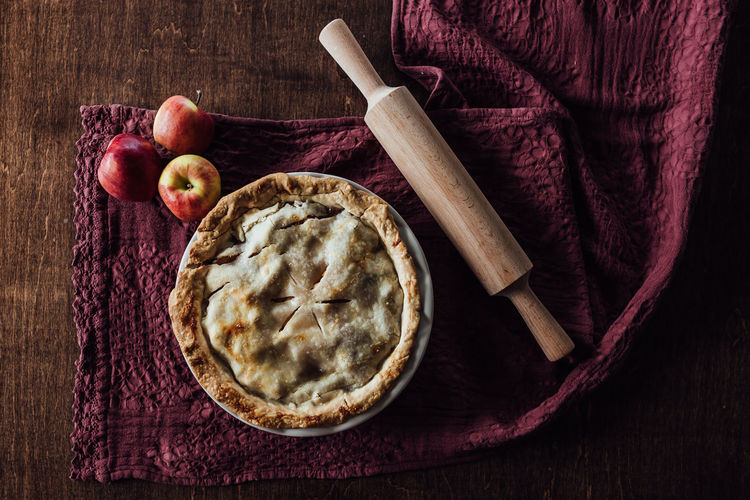 Overhead shot of apple pie with apples and rolling pin
