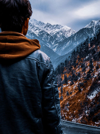 Rear view of man looking at snowcapped mountain