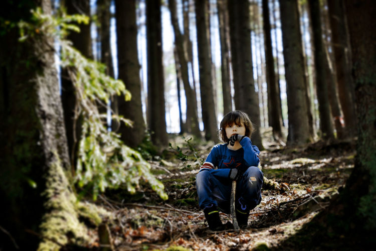 Full length of a boy sitting on sidewalk in forest