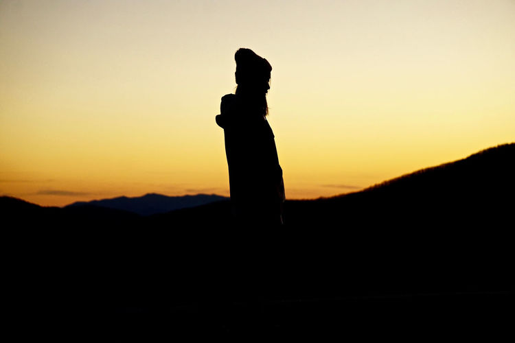 Silhouette woman against orange sky during sunset