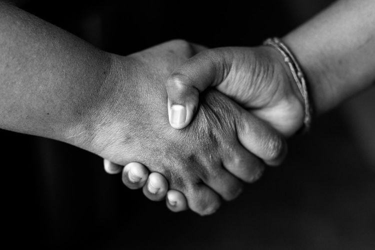 Cropped image of people shaking hands against black background