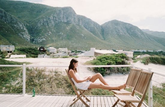 Woman sitting on chair against mountains