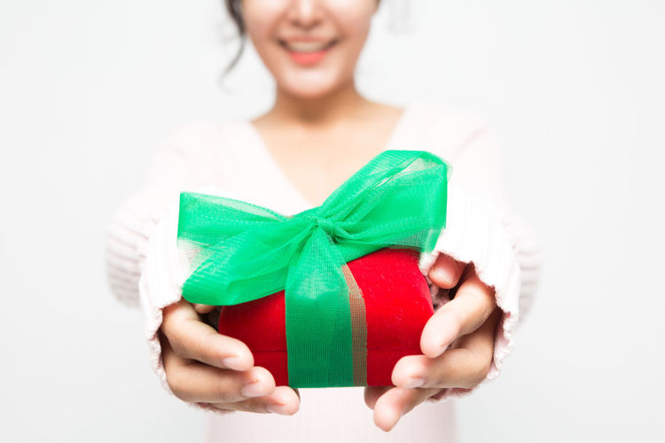 Portrait of woman holding gift against white background