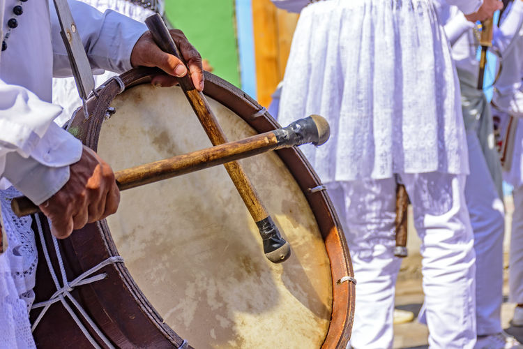 Midsection of man playing drum by crowd during festival 