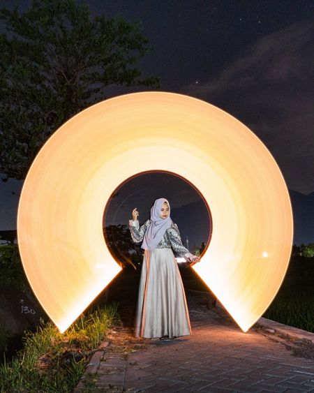 Woman standing with light painting against sky at night