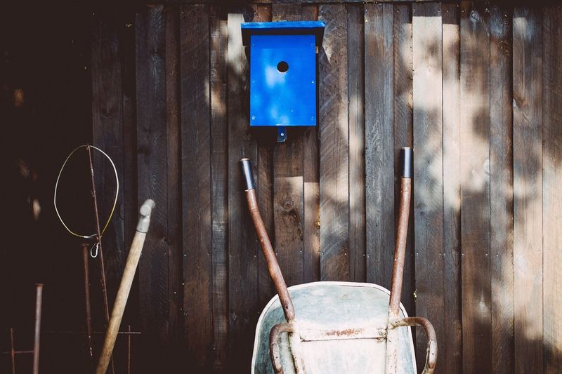 Birdhouse with wheelbarrow against wooden wall
