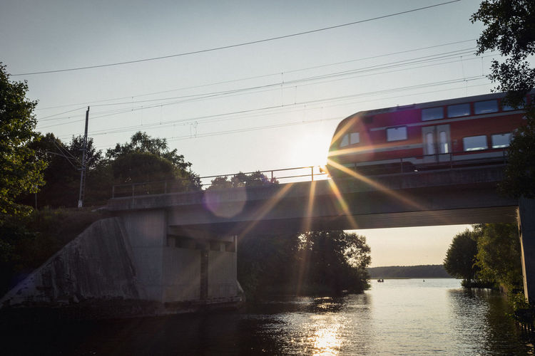 Low angle view of train on bridge over river during sunny day