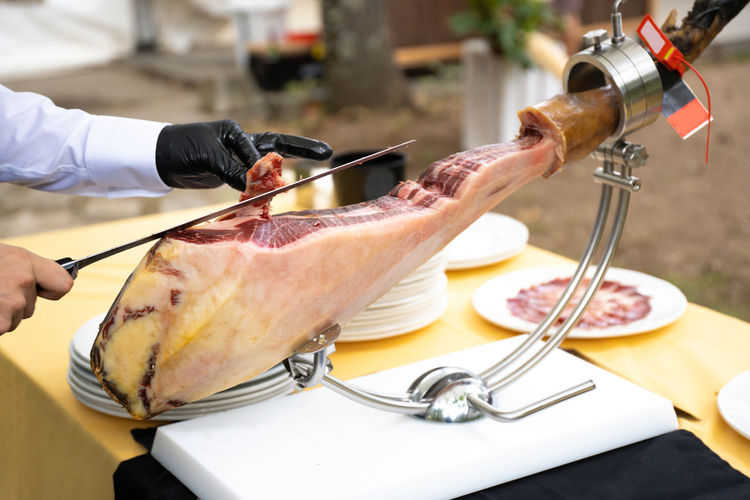 Ham cutter with gloves at a party cutting thin slices of iberian ham