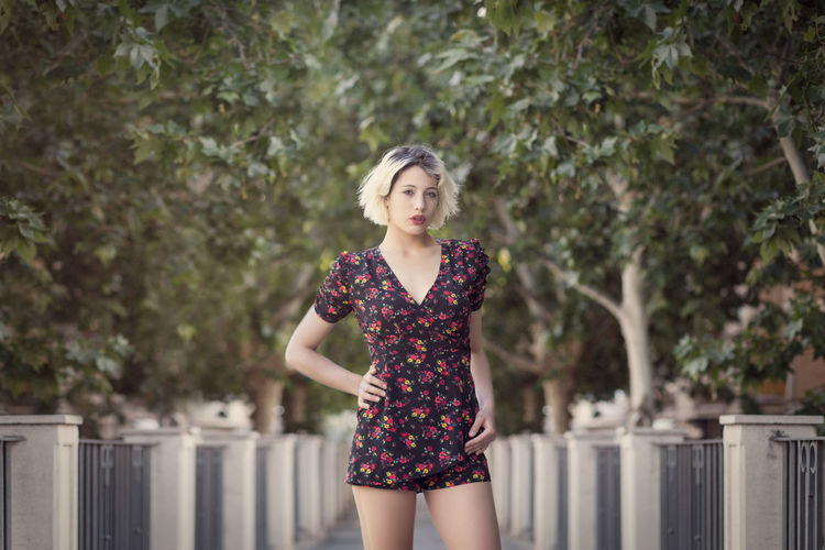 Portrait of a beautiful young woman standing against trees