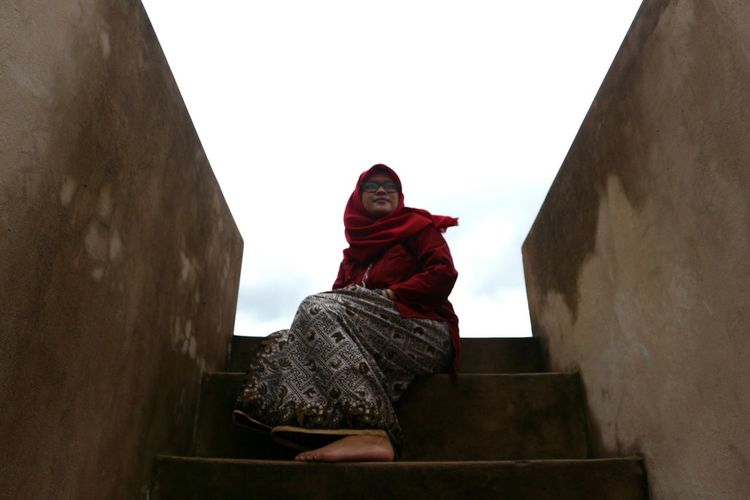Low angle view of woman sitting on steps against sky