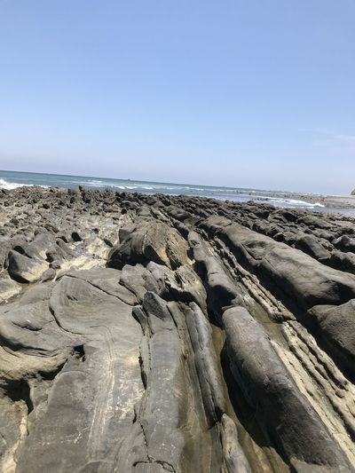 Panoramic view of rocks on beach against clear sky