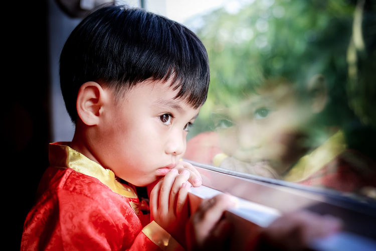 Close-up of boy looking away through window