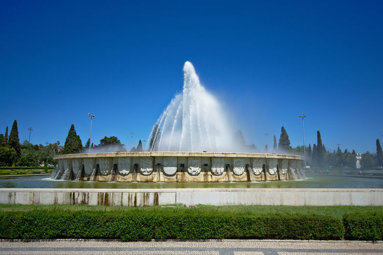 Fountain in park against blue sky
