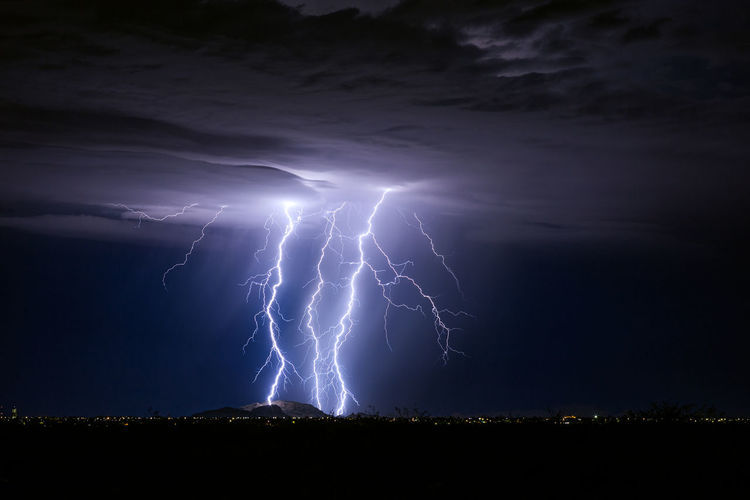 Powerful lightning bolts strike a mountain during a monsoon storm near casa grande, arizona.