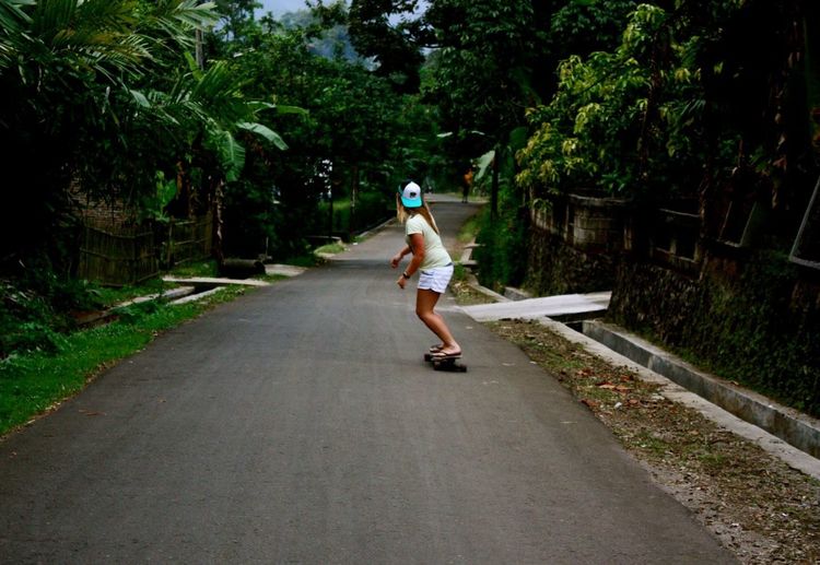 Full length of woman skateboarding on road