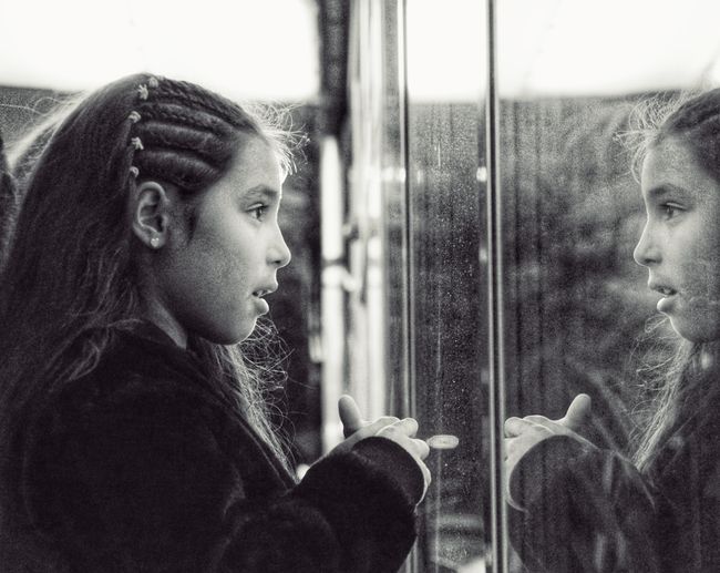 Girl looking through window at home