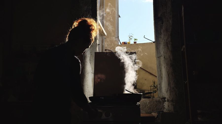 Rear view of woman cooking food in darkroom