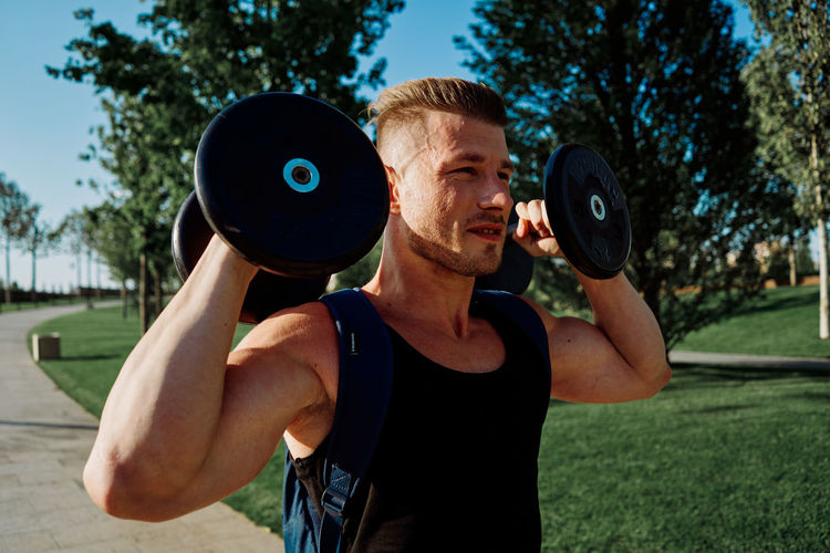 Man exercising with dumbbells at park