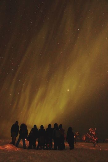Silhouette people standing on snow covered field against star field at night