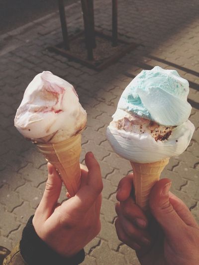 Cropped image of friends holding ice creams on sidewalk
