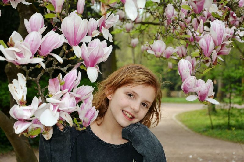 Portrait of smiling girl by flowers at park