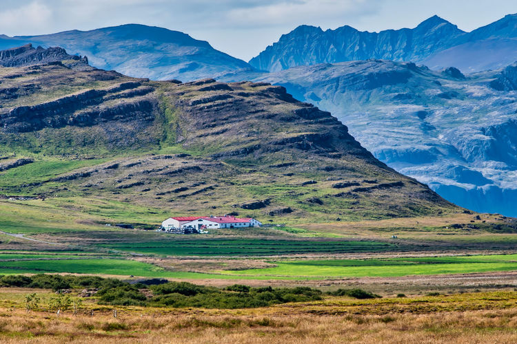 Scenic view of landscape with house against mountains and sky. 