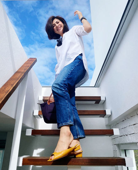 Low angle view of smiling woman standing on staircase