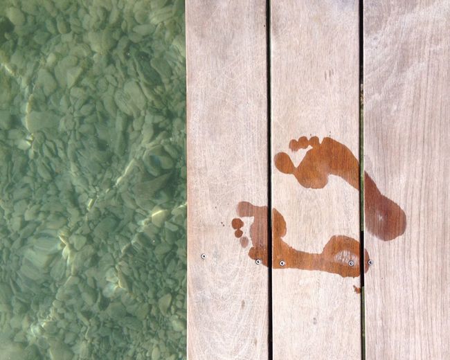 Directly above shot of footprints on pier over lake