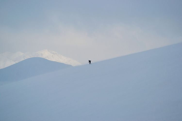 Mid distance view of man on snowcapped mountain against sky