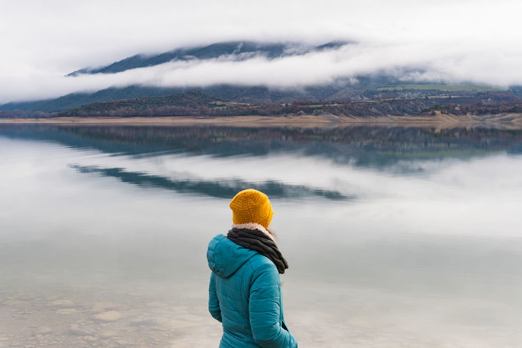 Traveler unrecognizable woman looking the fog on the mountains in the other side of the lake