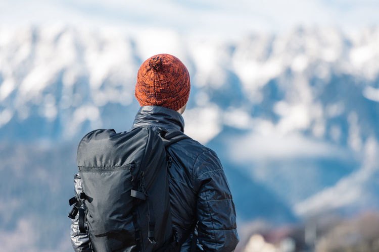 Man hiking in winter and admiring the amazing view towards the mountains people and places.