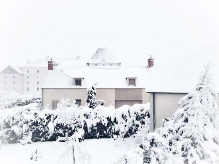 Snow covered houses by building against sky