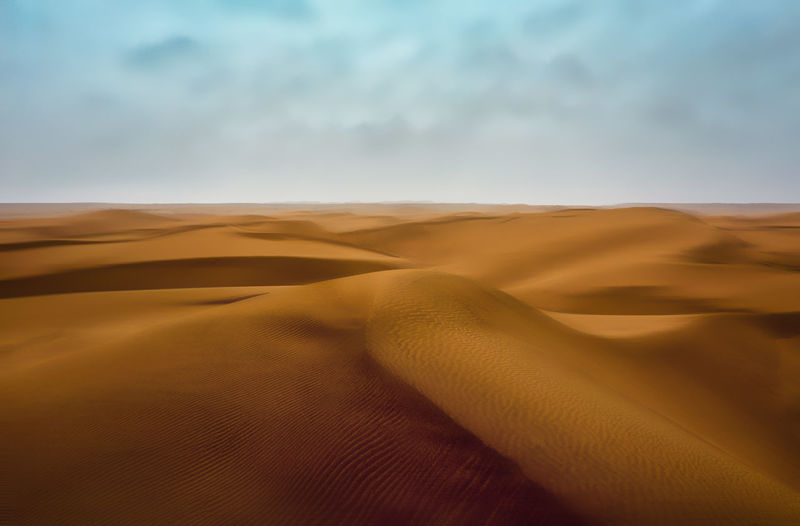 Sand dunes in desert against sky