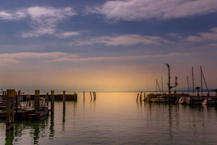 Wooden posts in sea at sunset