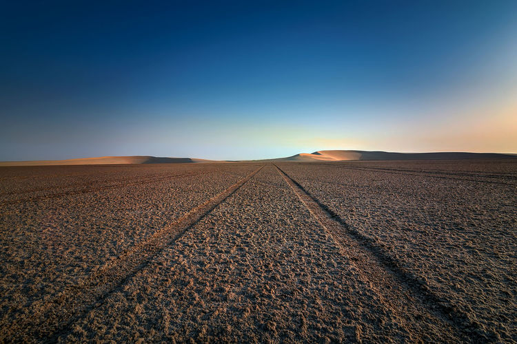 Scenic view of desert against clear sky during sunset