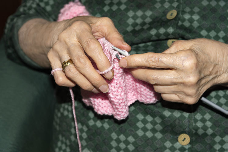 Midsection of senior woman knitting wool at home