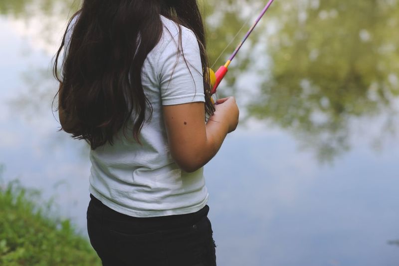 Midsection of woman fishing in lake