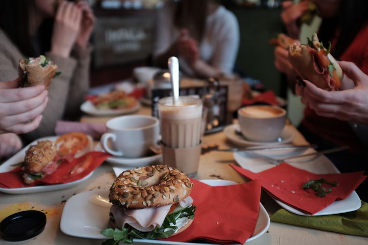 Cropped image of people eating bagels at restaurant