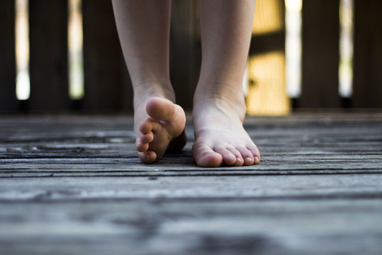 Low section of person standing on wooden floor
