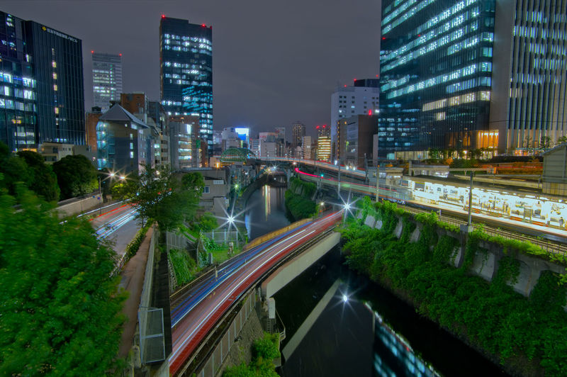 Light trails on road amidst buildings in city at night