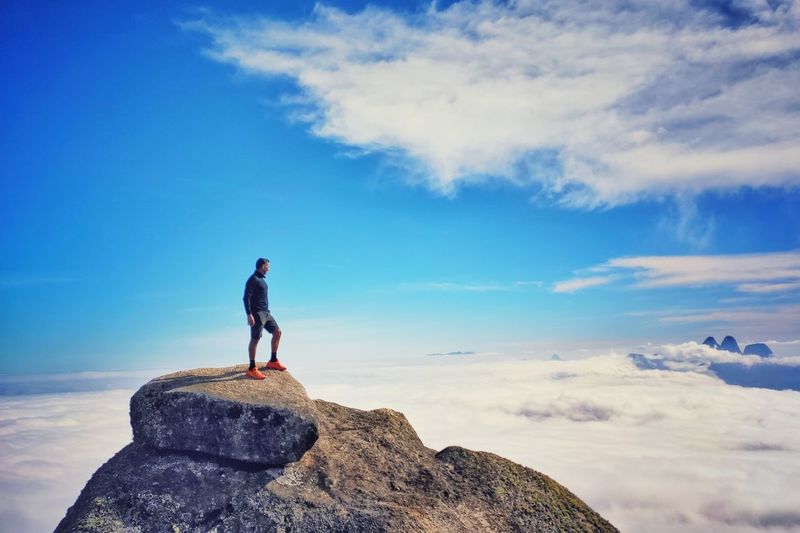 Man standing on rock against sky