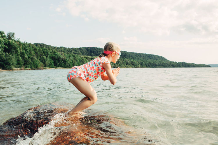 Side view of girl jumping in river